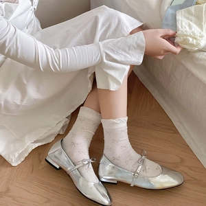 Detail of silver Mary Jane shoes and white calf-high socks with bow jacquard texture