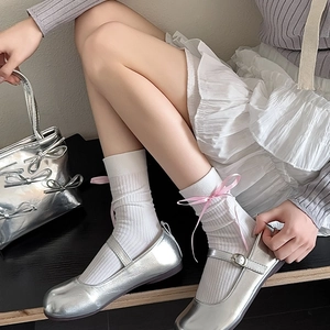 Détail de chaussures Mary Jane argentées avec chaussettes blanches et nœuds roses
