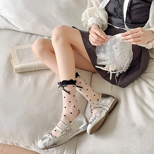 Detail of sheer polka dot socks with bow accents and silver Mary Jane shoes