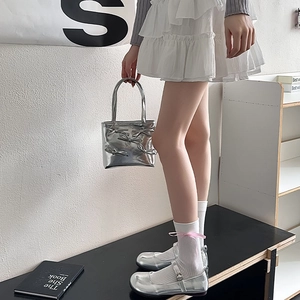 Sac argenté avec nœud associé à des chaussures Mary Jane et une jupe blanche à volants