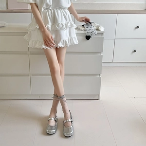 Sheer grey polka dot socks with satin bow detail paired with silver Mary Jane shoes