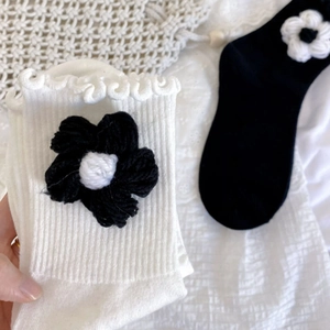 Close-up of handmade crochet flower socks with ruffle edges in classic black and white