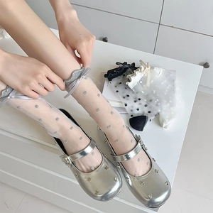 Close-up of grey polka dot sheer socks with ribbon bow paired with silver Mary Janes