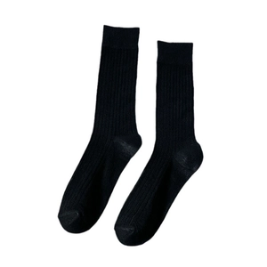 Chaussettes noires à mi-mollet avec texture côtelée verticale sur fond blanc neutre