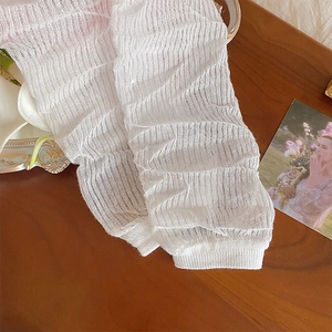 Dettaglio di scaldamuscoli in pizzo bianco con trama a rete su sfondo legno vintage