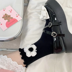 Detail of ruffle cuff socks with knit 3D flower paired with black Mary Jane shoes