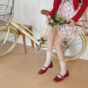 Gros plan de chaussettes en dentelle florale évidée avec chaussures Mary Jane rouges