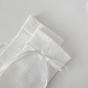 Gros plan de chaussettes JK blanches à côtes avec un délicat nœud en satin au revers