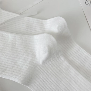 Détail de bas JK blancs avec texture en maille côtelée et rubans de soie délicats