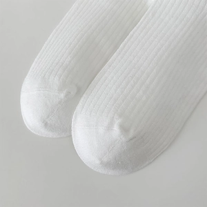 Gros plan détaillé des chaussettes blanches côtelées montrant la couture des orteils