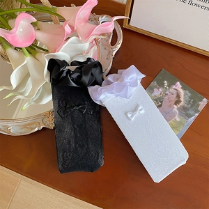 Detailed shot of black and white lace mesh socks with satin ruffles and bow accents