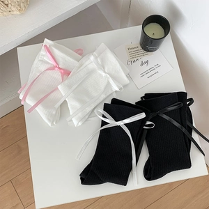 Vue détaillée de chaussettes blanches côtelées avec un ruban décoratif rose doux