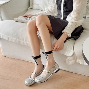 Detail of silver Mary Jane flats with star studs and bow sheer socks on model