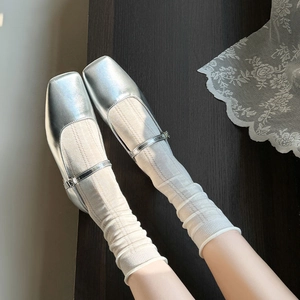 Close-up of silver square toe Mary Jane shoes styled with white textured mesh socks