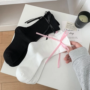 Détail de chaussettes JK noires et blanches avec nœuds en ruban sur fond blanc