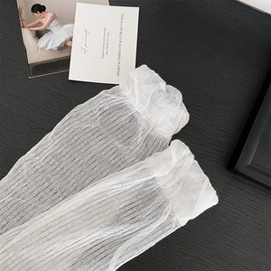 Close-up of white mesh leg warmers with delicate ruffle edges on wood background
