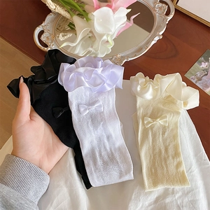 Close-up of elegant lace mesh socks with silk bows and ruffled trim in three colors
