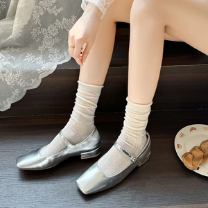 Detail of silver metallic Mary Jane shoes paired with beige knitted crew socks on stairs