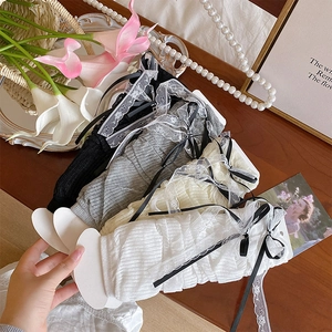 Manicotti Lolita con pizzo e fiocchi in nero grigio crema e bianco su legno