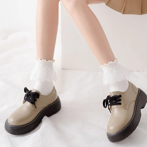 Detail of white Lolita lace socks paired with beige thick-sole platform derby shoes