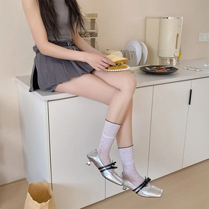 Détail de talons aiguilles argentés avec nœuds noirs et chaussettes en dentelle chic