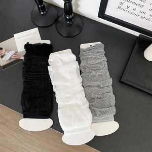 Detailed close-up of ribbed knit leg warmers in black, white, and grey color options