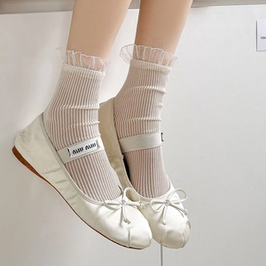 Close-up of white lace mesh socks paired with satin ballet flats and ribbon detail
