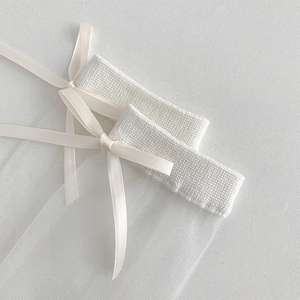 Detail of white sheer tulle socks with knit rib cuffs and delicate ribbon bow decoration