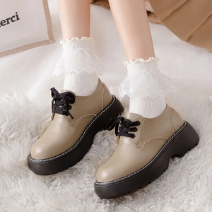 Close-up of white Lolita lace ruffles on mid-calf socks paired with retro platform shoes