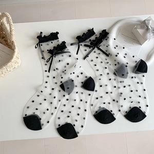 Detailed view of sheer polka dot mesh socks with elegant black ruffles and bow details
