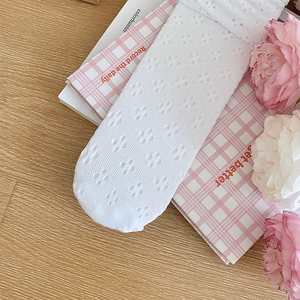 Détail de chaussettes blanches en dentelle ajourée sur un fond à carreaux roses