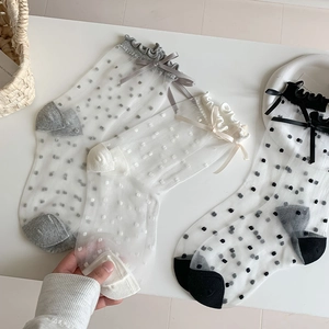 Detail of polka dot sheer socks with delicate ruffle trim and satin bow accents