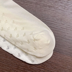 Detailed close-up of white heart hollow-out knit mesh socks on a wooden texture background