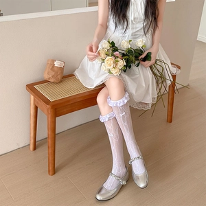 Close-up of white lace mesh knee-high socks with ruffled edges and ribbon bows