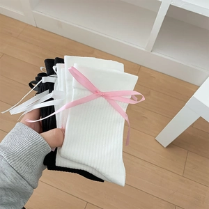 Détail de chaussettes mi-hautes en coton noir et blanc avec nœuds en soie et rayures verticales