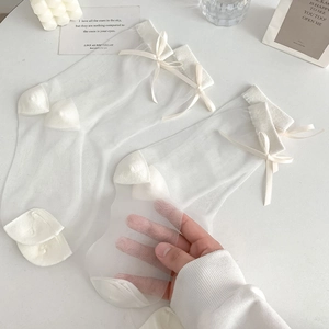 Close-up of white sheer mesh socks featuring a delicate satin bow and transparent texture