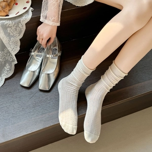 Detail of white hollow mesh socks with striped knit texture and slouchy cuffs