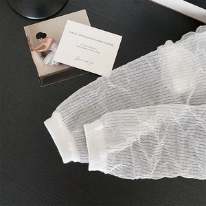 Close-up of white mesh sun protection sleeves with ripple texture and ribbed cuffs