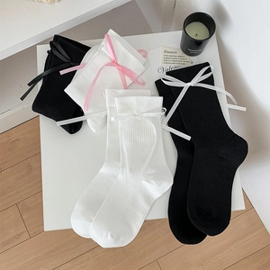 Détail de chaussettes JK noires et blanches à côtes avec des nœuds décoratifs