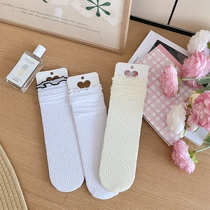 Détail de chaussettes hautes à volants avec motif fleuri ajouré et emballage d'origine
