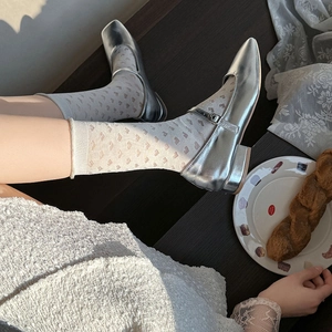 Detail showing silver Mary Jane flat shoes with heart pattern mesh socks and tweed dress