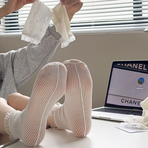 Detailed close-up of white lace mesh socks with ruffled edges and sheer floral pattern