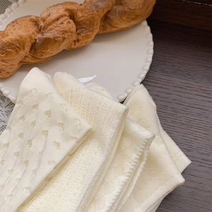 Detail of white mesh socks with heart patterns on a white plate with pastry