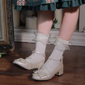 Détail de chaussures Mary Jane crème avec perles, nœuds et chaussettes en dentelle