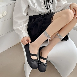 Sheer skin-tone socks with grey bow detail paired with black Mary Jane shoes