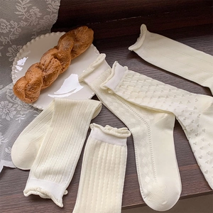 Detail of white hollow mesh socks featuring delicate ruffle cuffs and vintage patterns