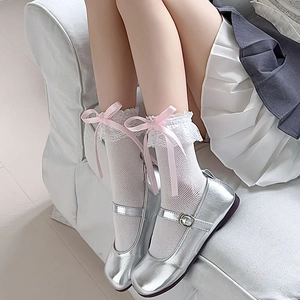 Détail de chaussettes en dentelle blanche avec nœuds roses et babies argentées