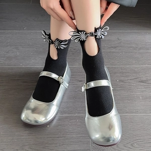 Silver Mary Jane shoes with heart buckles and black ankle socks on dark wood floor