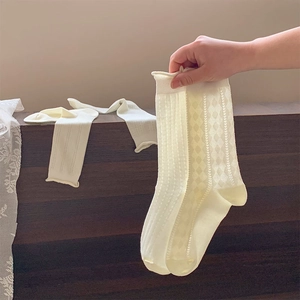 Detailed view of cream mesh socks featuring hollow diamond patterns and curled edges