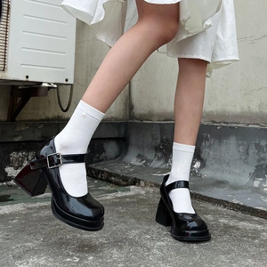 Close-up of black patent leather platform Mary Jane shoes with white heart pattern socks